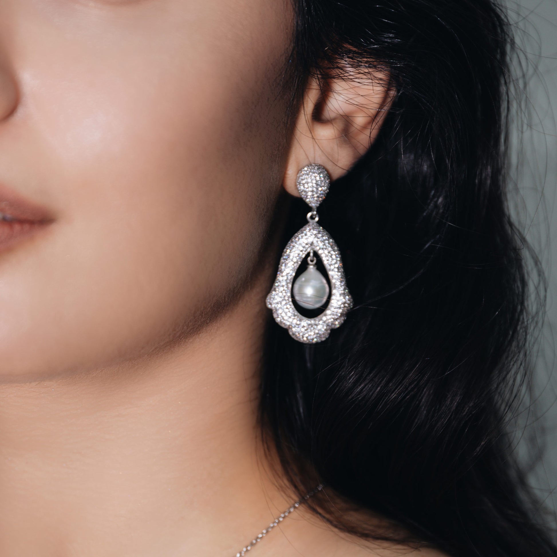 Baroque pendant earrings with in the shape of a flat bell with a dangling pearl inside 