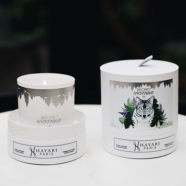 secret mystique scented candle in white cylindrical packaging with a wolf in the forest